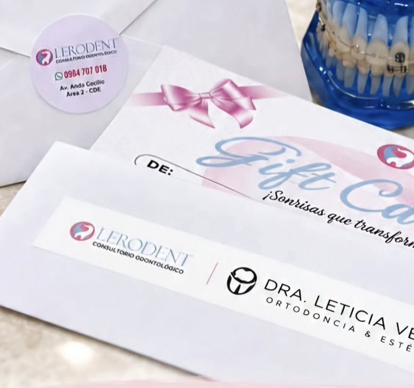 Sobre con sticker de Lerodent, la gift card con moño rosa y un modelo dental con brackets
